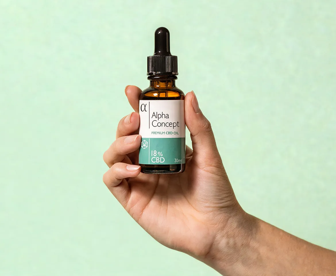 Ruka drži bočicu Alpha Concept CBD ulja 18% na mint zelenoj pozadini